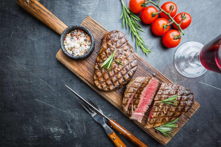 Grilled marbled meat steak Filet Mignon with seasonings. Juicy beef steak on cutting board, top view.